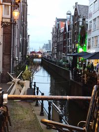 Canal amidst buildings in city against sky