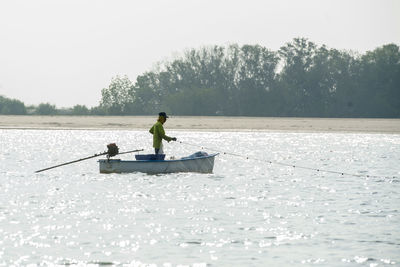 Man on boat in lake against sky