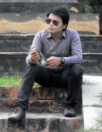 Full length of young man sitting outdoors