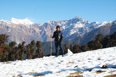 Man standing on snowcapped mountain against sky