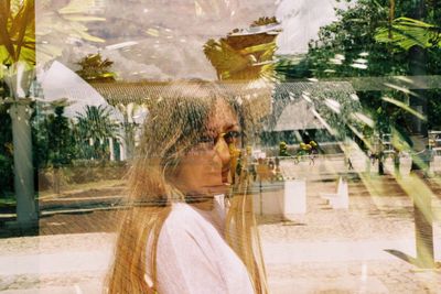 Side view of woman looking through palm trees