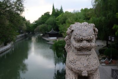 Statue against trees and plants against sky