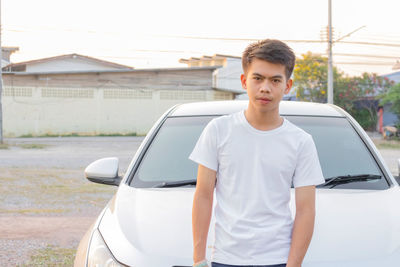 Portrait of young man standing on car