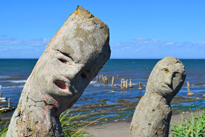 Close-up of stone post in sea against sky