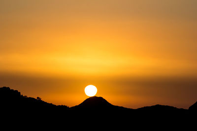 Scenic view of silhouette mountains against romantic sky at sunset