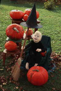 Full length of boy holding pumpkin on field during autumn