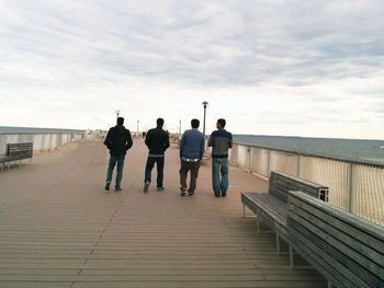 Rear view of people standing on railing against sea