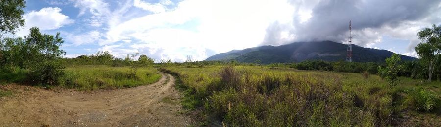 Panoramic shot of road amidst field against sky