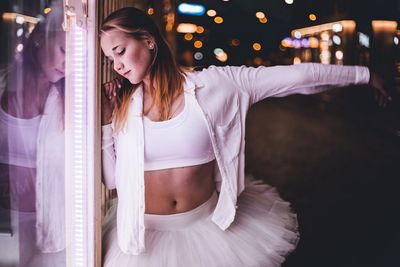 Beautiful young woman looking away while standing at night