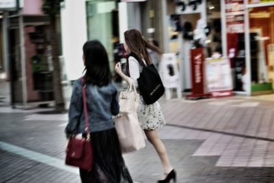 Full length of woman with umbrella on city street