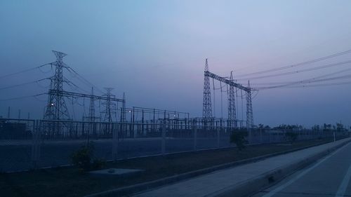 Electricity pylon by road against sky