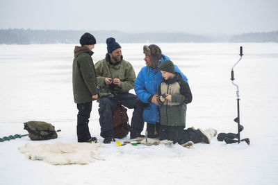 Cheerful male friends enjoying with sons at frozen lake