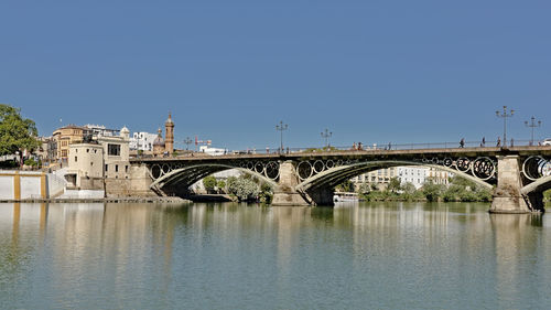 Arch bridge over river against clear blue sky