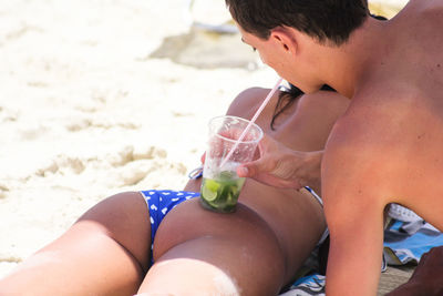 Close-up of shirtless boy drinking water at beach