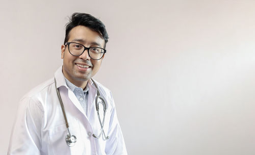 Portrait of young man standing against white background