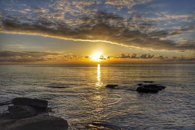 Scenic view of sea against dramatic sky during sunset