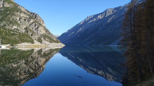 Scenic view of lake and mountains against clear blue sky