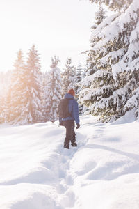 Rear view of man skiing on snow covered field