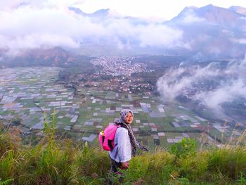 Woman standing by mountain against sky