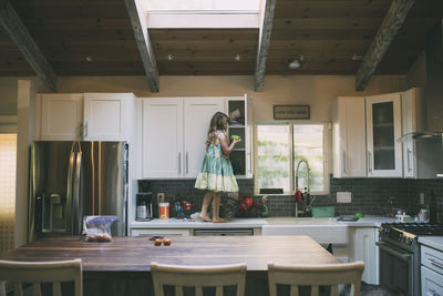 Side view of girl standing on kitchen counter