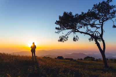 Man standing on field against sky during sunset