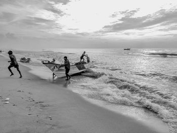 People at beach against sky