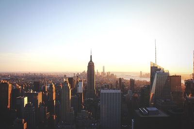 Empire state building and buildings in city against sky during sunset