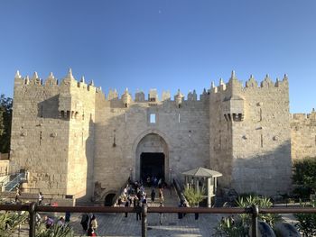 People at historic building against clear sky