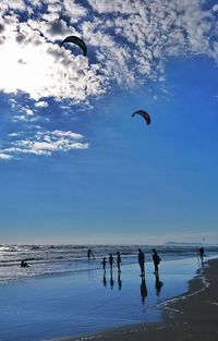 People enjoying at beach against sky