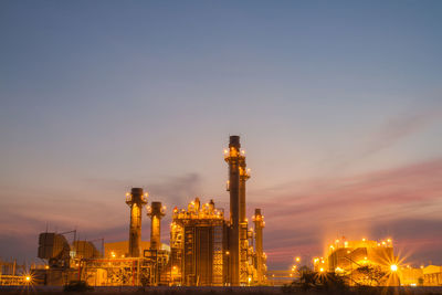 Illuminated factory against sky at night