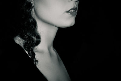 Close-up of young woman against black background