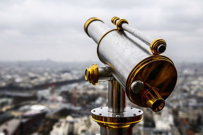 Close-up of coin-operated binoculars with cityscape in background