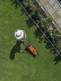 Woman with lawn mower standing in back yard