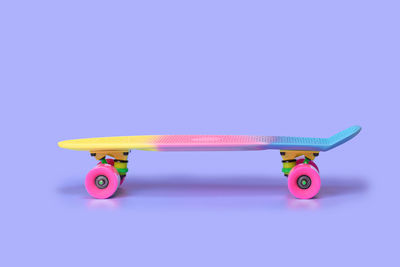 Rainbow plastic penny board skateboard isolated on purple background