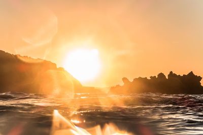 Surface level view of sea against bright sky during sunset