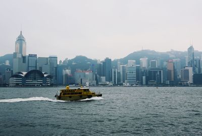 Boat in sea against buildings in city