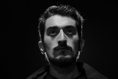 Portrait of young man against black background