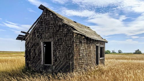 Abandoned house on field against sky