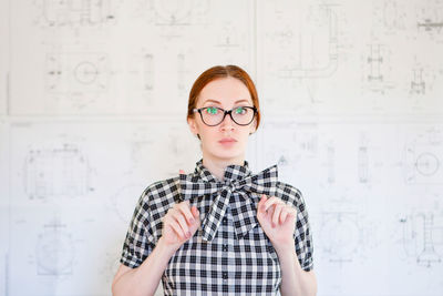 Young woman engineer with mechanical drawings on background