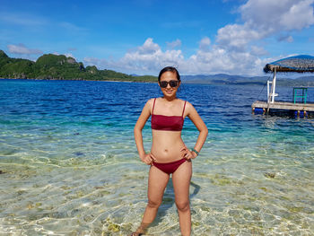 Full length portrait of woman standing in sea against sky