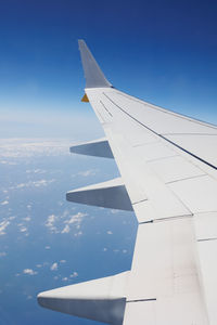 View from inside an aircraft- window of the cabin, white airplane wing and clouds.