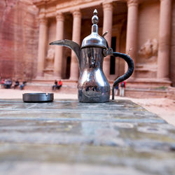 Close-up of old metal on table against building