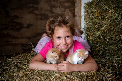 Smiling child with kittens posing in the barn on straw bales