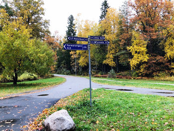 Road sign by trees during autumn