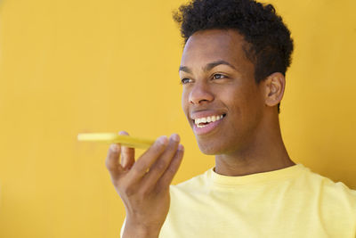 Portrait of a smiling young man against yellow background