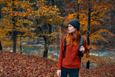 Full length of young woman standing in autumn tree