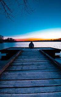 Rear view of man on pier at sunset