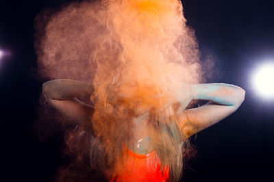 Close-up of woman with power paint standing against black background