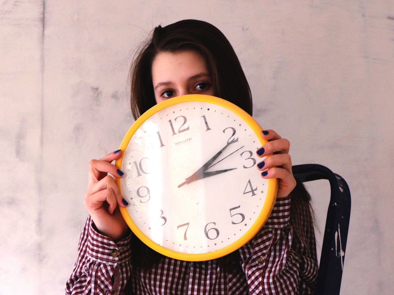 communication, text, lifestyles, western script, front view, person, leisure activity, holding, young adult, indoors, portrait, casual clothing, looking at camera, time, close-up, wall - building feature, waist up, clock