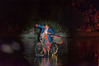 Man riding bicycle on river at night